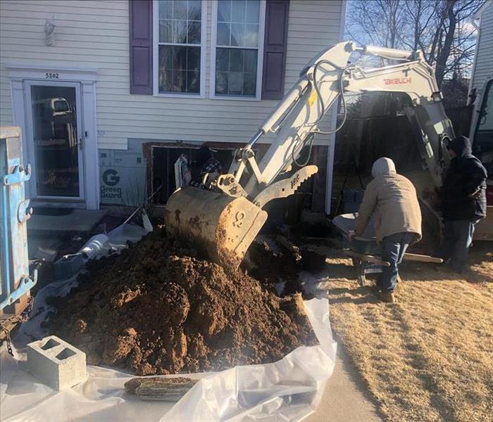 Large equipment digging up foundation of house.